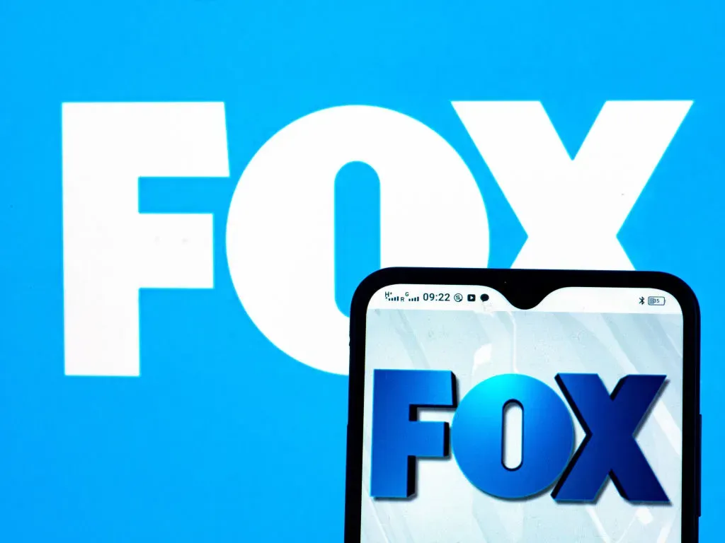  In this photo illustration Fox Broadcasting Company logo seen displayed on a smartphone and in the background.