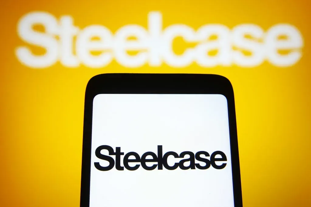 In this photo illustration, Steelcase Inc. logo is seen on a smartphone and a computer screen. 