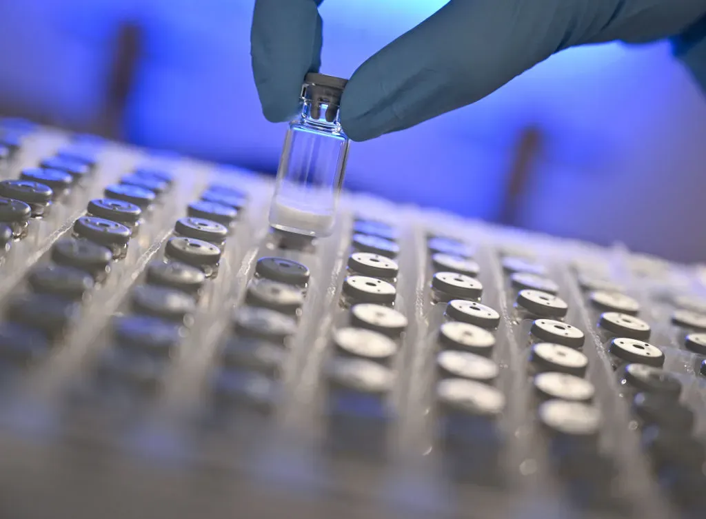 Biology lab technician removes a freeze-dried sample from a container in a laboratory.