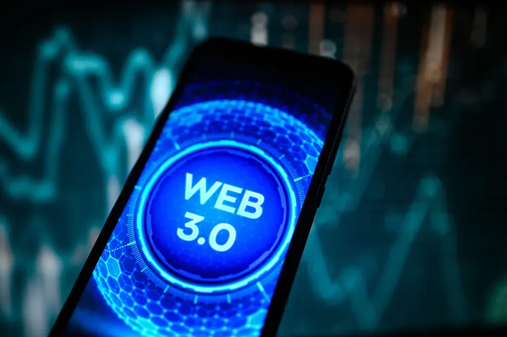In this photo illustration, a Web 3.0 logo is displayed on a smartphone with a line graph in the background.
