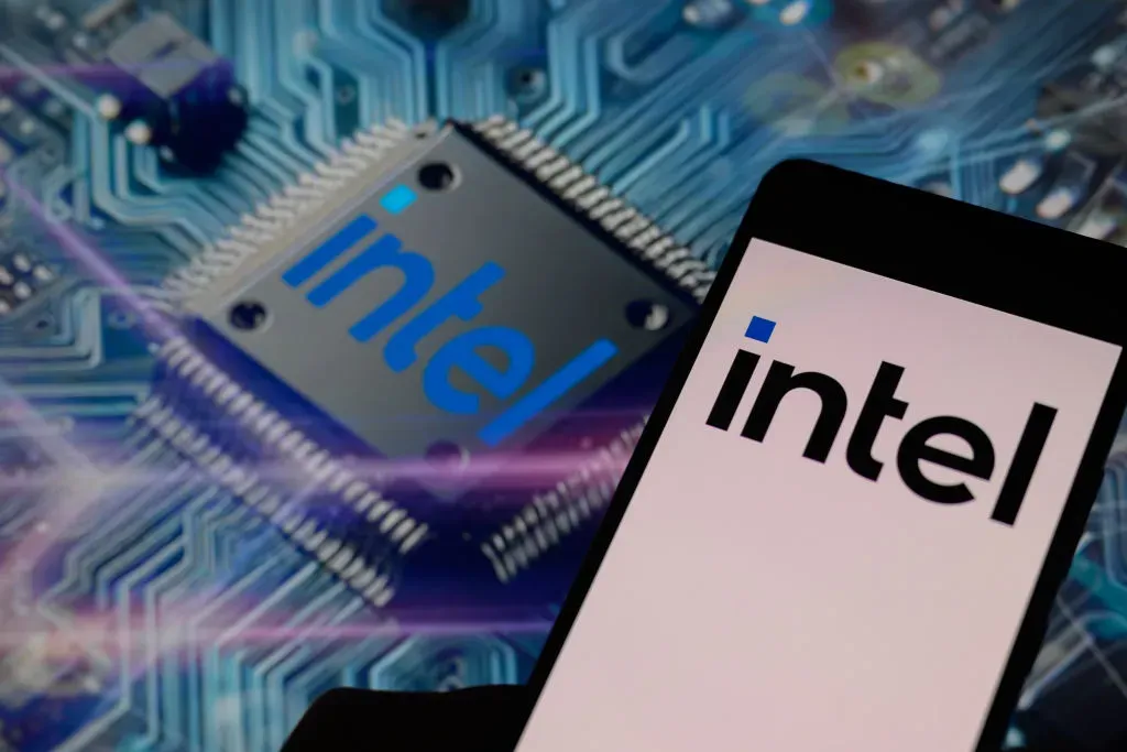 The Intel Corporation logo is being displayed on a smart phone, with an Intel chip visible in the background.
