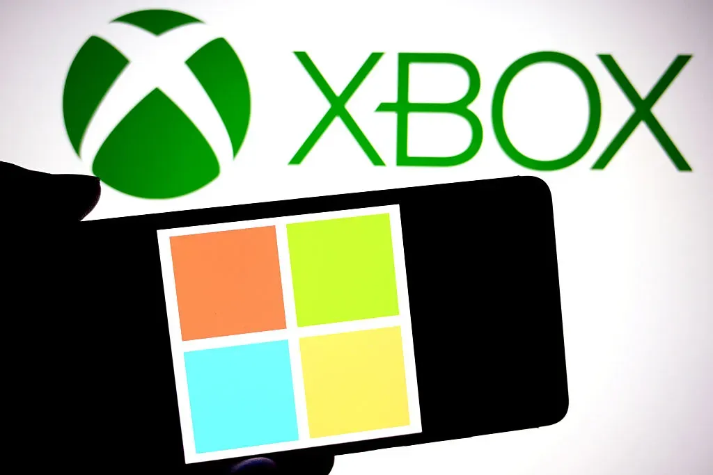 In this photo illustration, a Microsoft logo is seen displayed on a smartphone with a XBOX logo in the background.