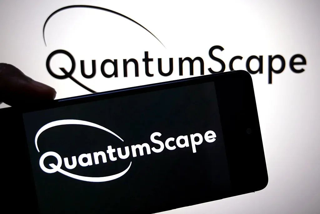 In this photo illustration, a QuantumScape logo is seen displayed on a smartphone and in the background. 