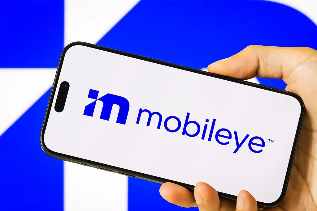 In this photo illustration, a person holds a smartphone displaying the logo of Mobileye Global Inc.