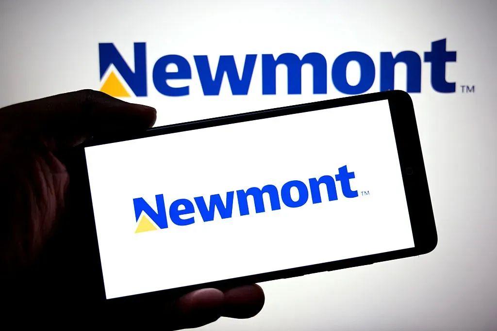 In this photo illustration, a Newmont logo is seen displayed on a smartphone and in the background. 