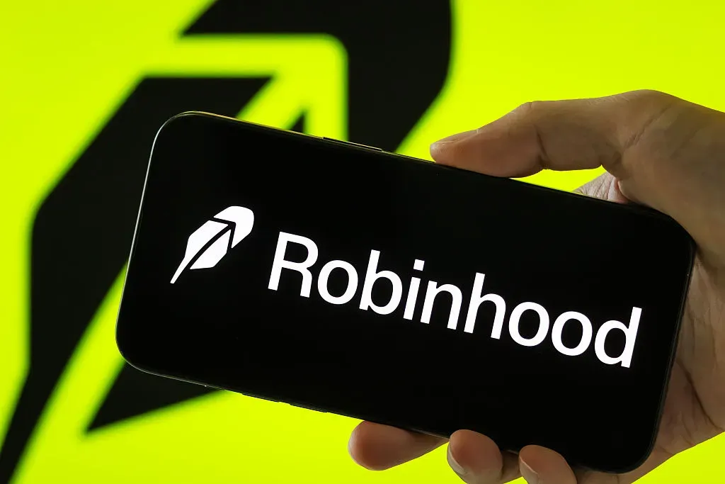 In this photo illustration, a person holds a smartphone displaying the logo of Robinhood Markets Inc. 