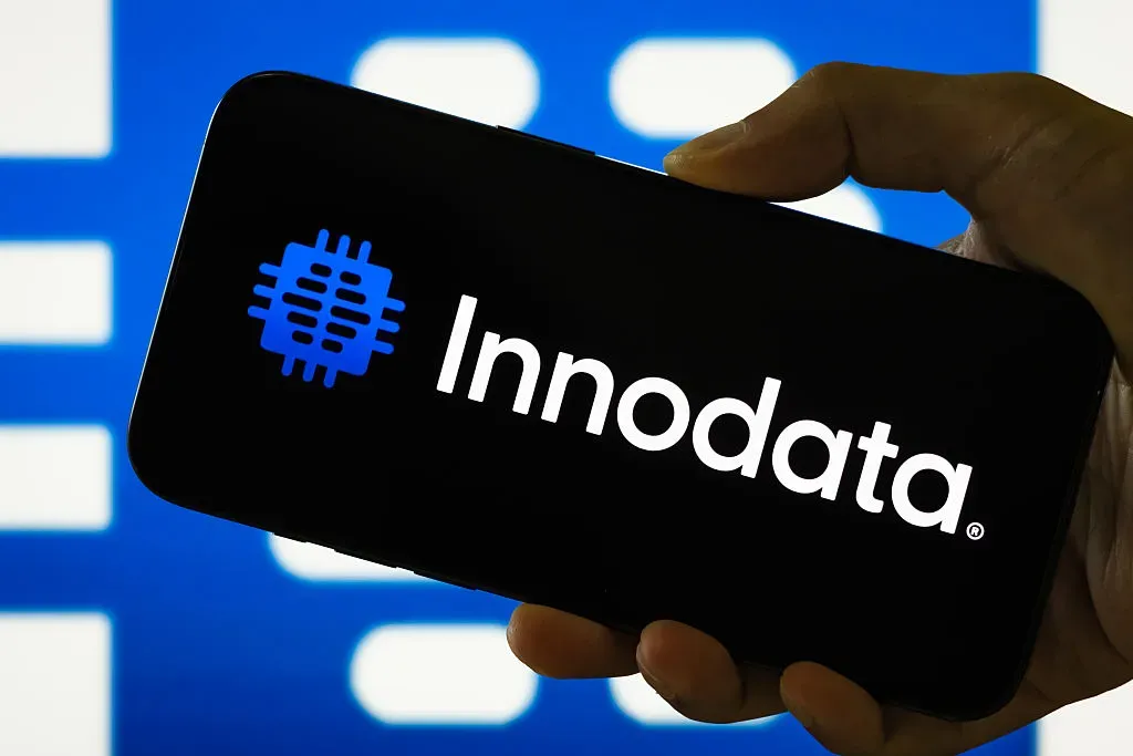 In this photo illustration, a person holds a smartphone displaying the logo of Innodata Inc.
