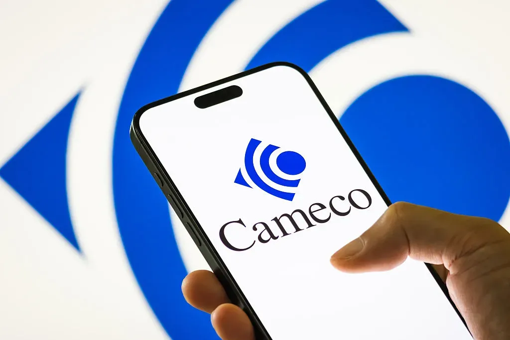 In this photo illustration, a person holds a smartphone displaying the logo of Cameco Corporation.