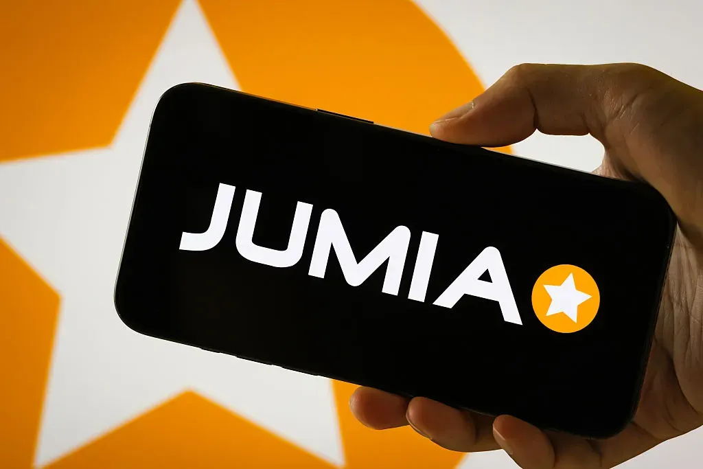 In this photo illustration, a person holds a smartphone displaying the logo of Jumia Technologies AG.
