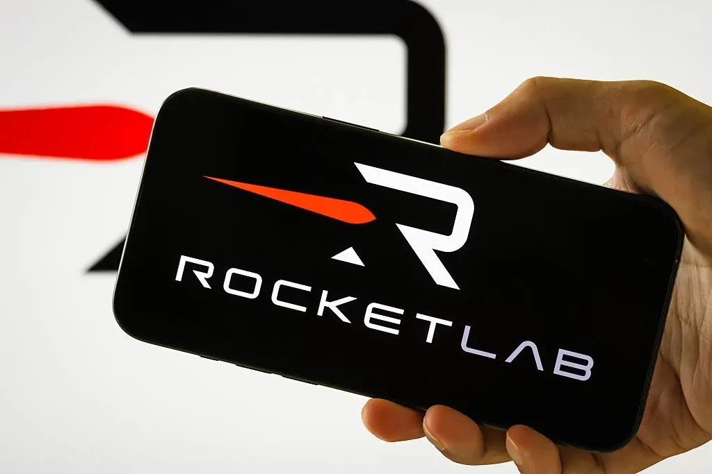 In this photo illustration, a person holds a smartphone displaying the logo of Rocket Lab USA Inc.