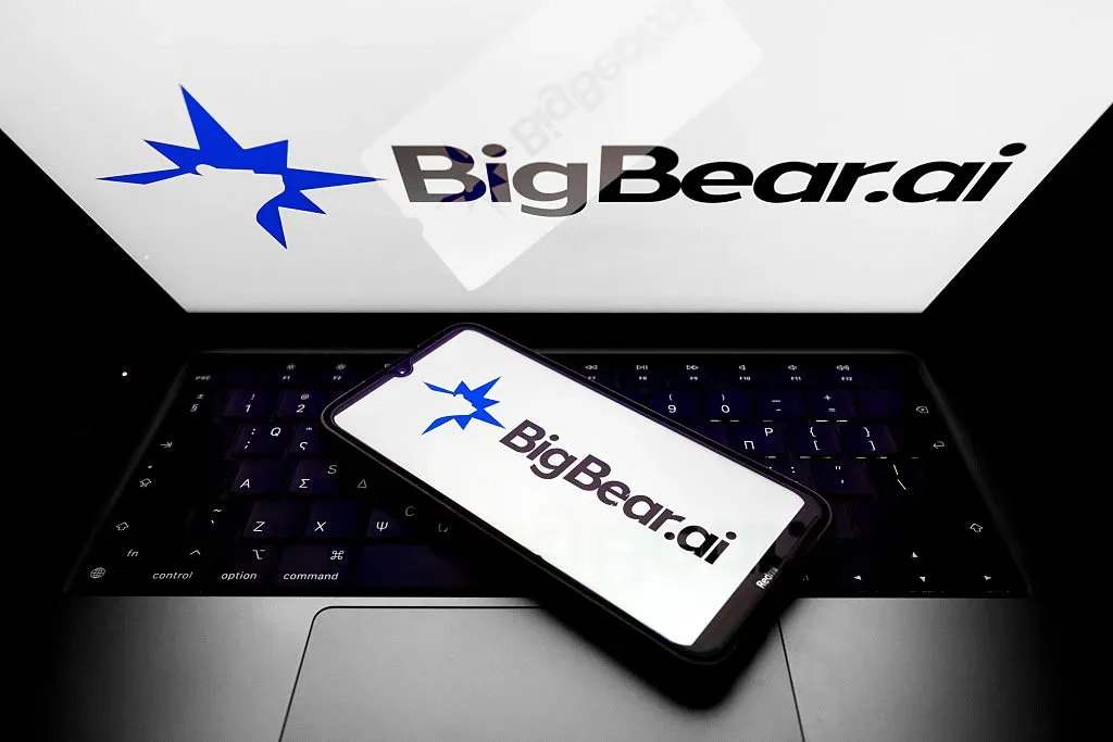The BigBear.ai Holdings Inc logo appears on a smartphone screen and as a background on a laptop screen in this photo illustration in Athens, Greece.