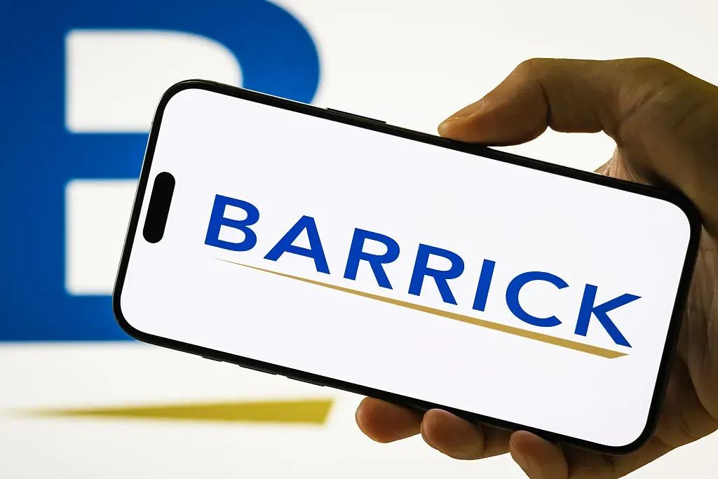 In this photo illustration, a person holds a smartphone displaying the logo of Barrick Mining Corporation.