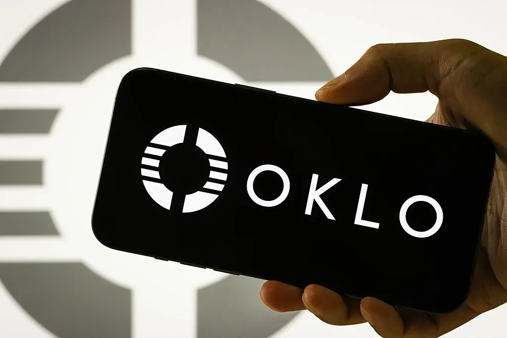 In this photo illustration, a person holds a smartphone displaying the logo of Oklo Inc.