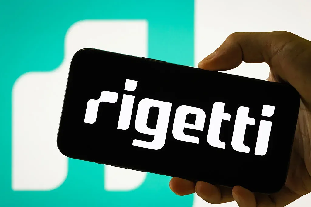 In this photo illustration, a person holds a smartphone displaying the logo of Rigetti Computing Inc.