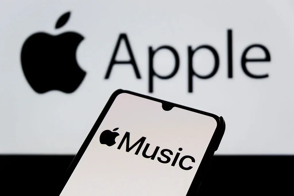 In this photo illustration, the Apple Music logo is seen displayed on a smartphone with an Apple logo in the background. 