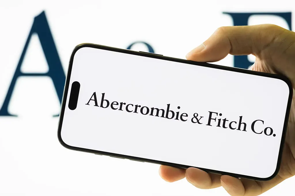 In this photo illustration, a hand holds a smartphone displaying the logo of Abercrombie & Fitch Co. 