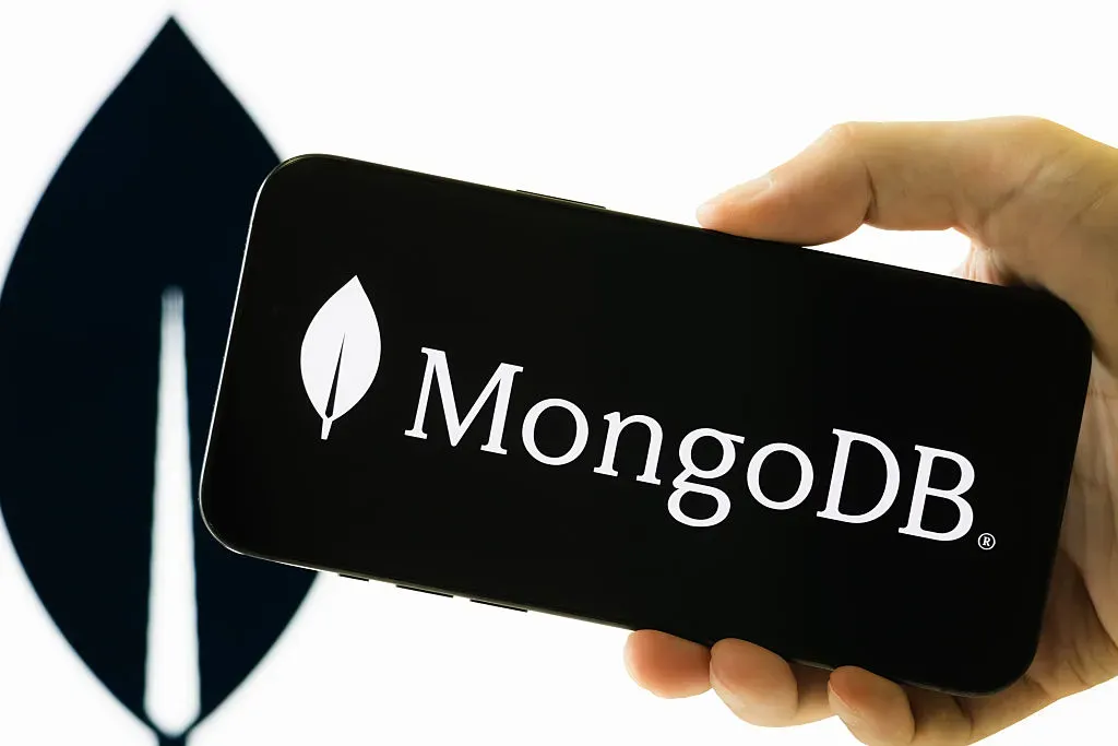 In this photo illustration, a hand holds a smartphone displaying the logo of MongoDB Inc.