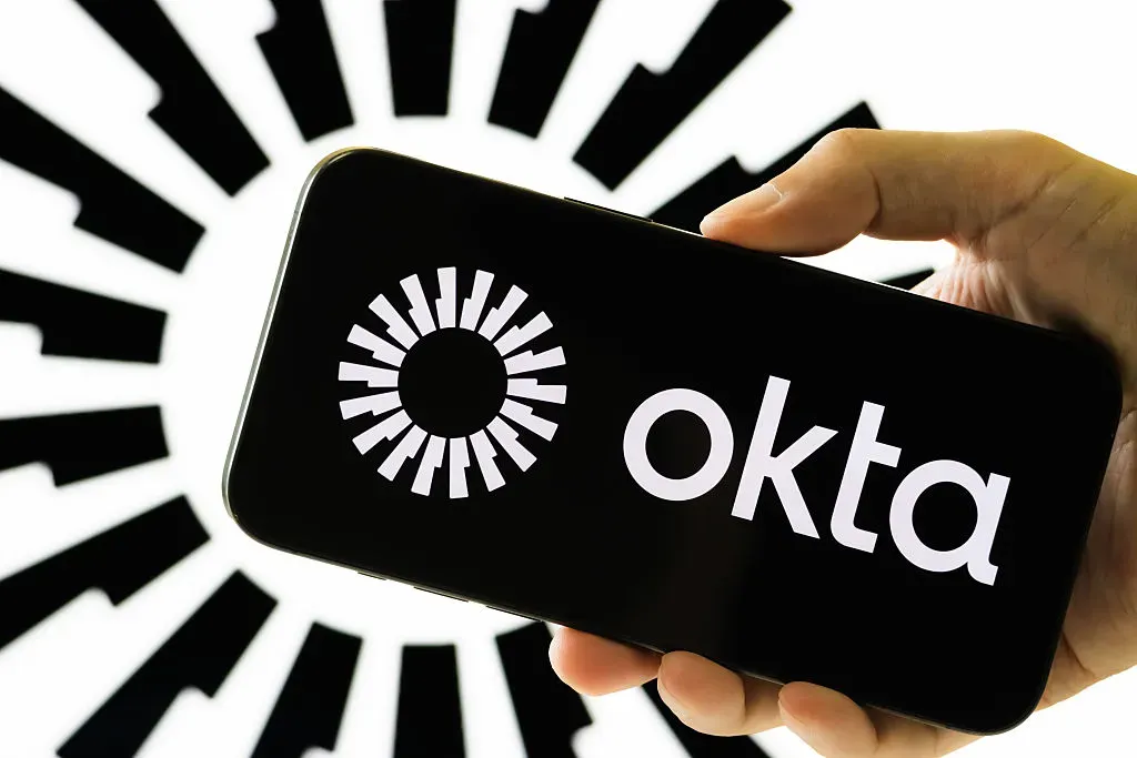 In this photo illustration, a hand holds a smartphone displaying the logo of Okta Inc.