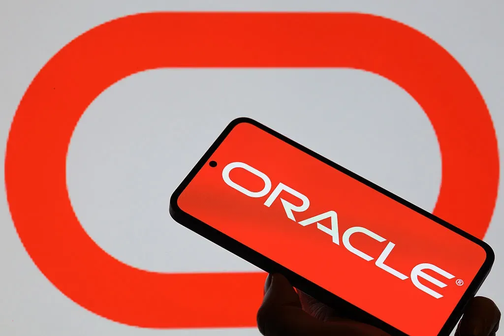 The Oracle logo is displayed on a mobile phone with the company's branding seen in the background in this photo illustration.