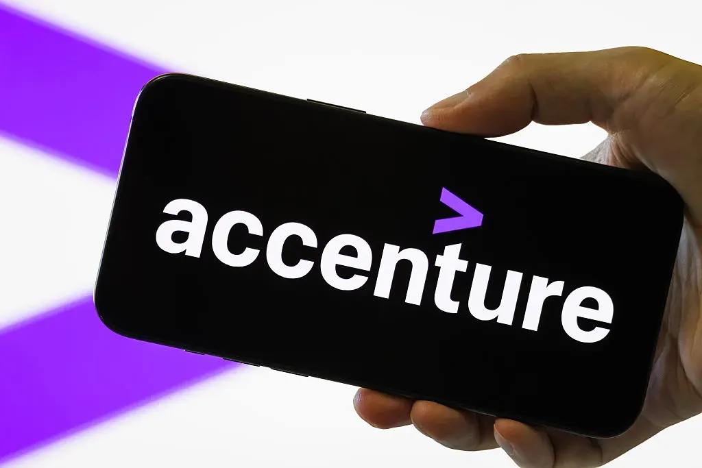 In this photo illustration, a smartphone held in a hand shows the logo of Accenture Plc.