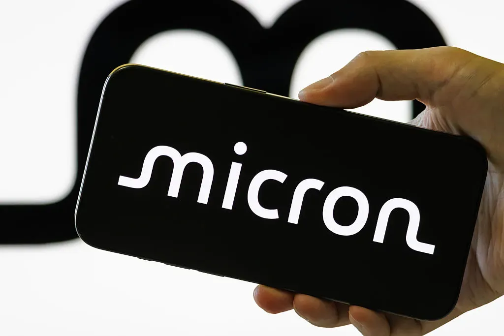 In this photo illustration, a smartphone held in a hand shows the logo of Micron Technology Inc. 