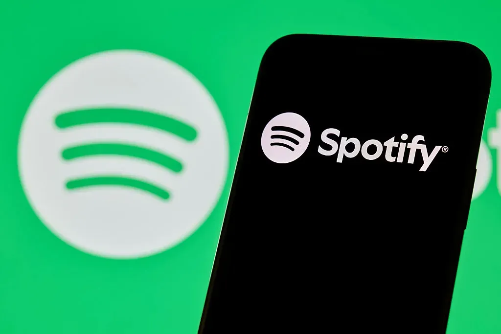 Close-up images show the Spotify logo and mobile application interface on a smartphone screen.