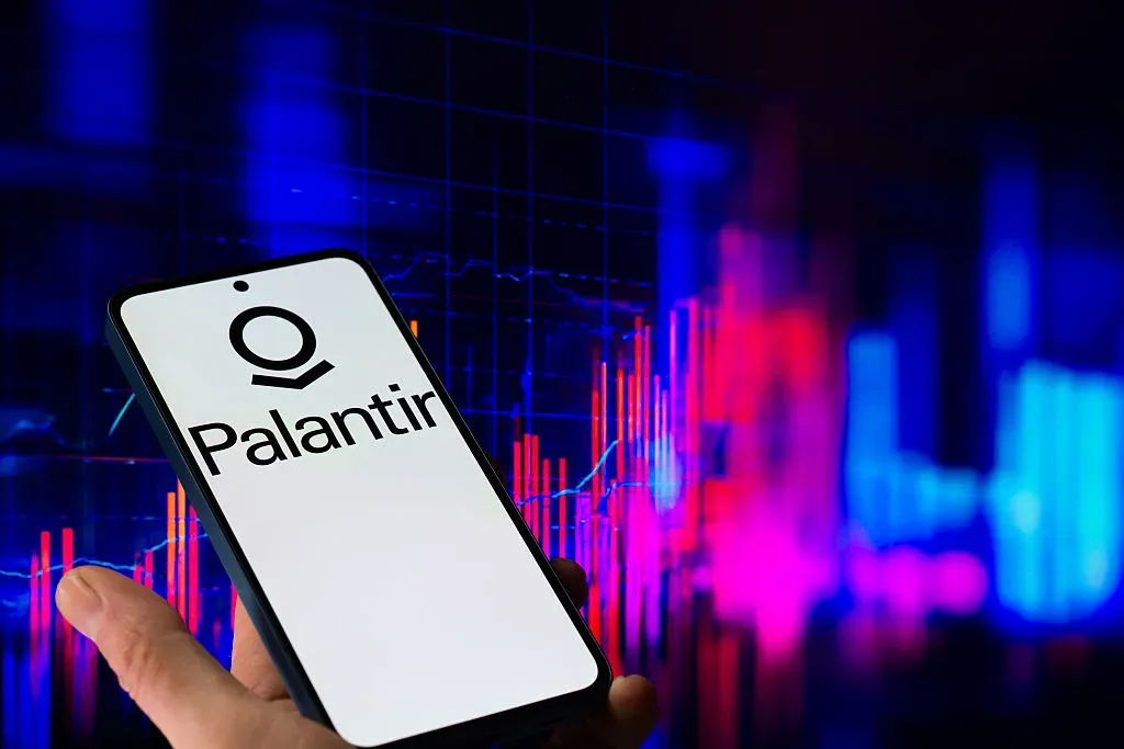 The Palantir logo is displayed on a mobile phone with a financial stock graph seen in the background, in this photo illustration in Brussels, Belgium, on November 3, 2025.