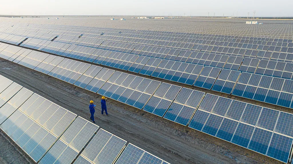 Workers are inspecting among large areas of photovoltaic solar panels in the Gobi wasteland.