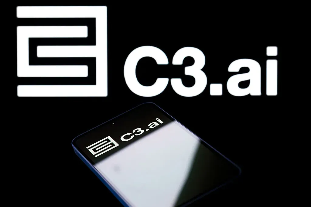 The C3.ai logo is displayed on a mobile phone with the company branding visible in the background.