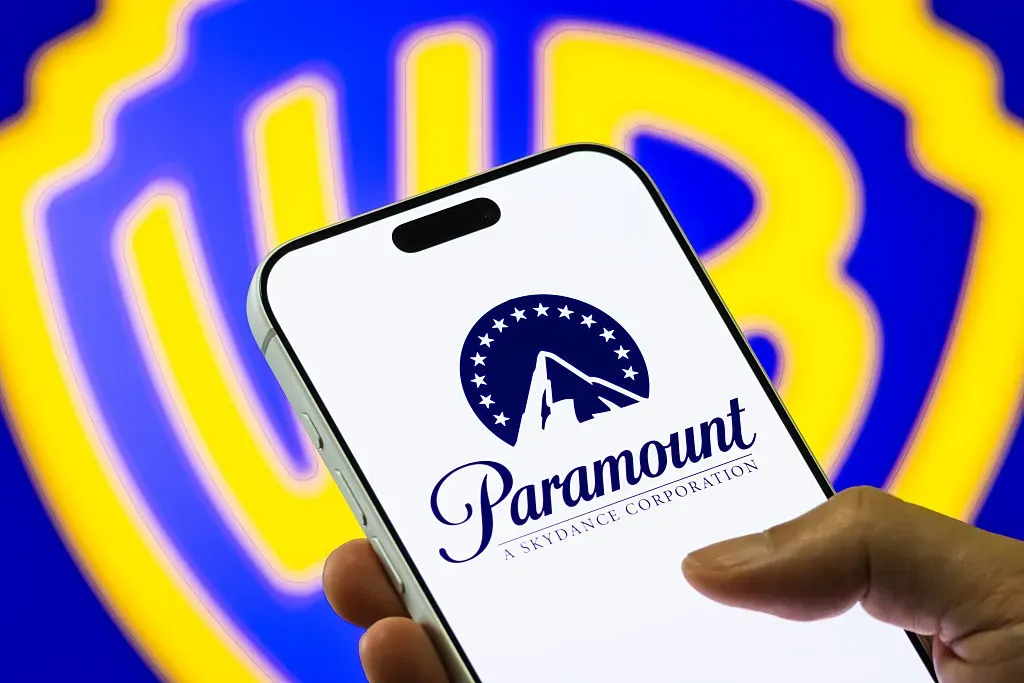 In this photo illustration, a smartphone displays the Paramount Skydance logo in front of a blurred Warner Bros. Discovery emblem.