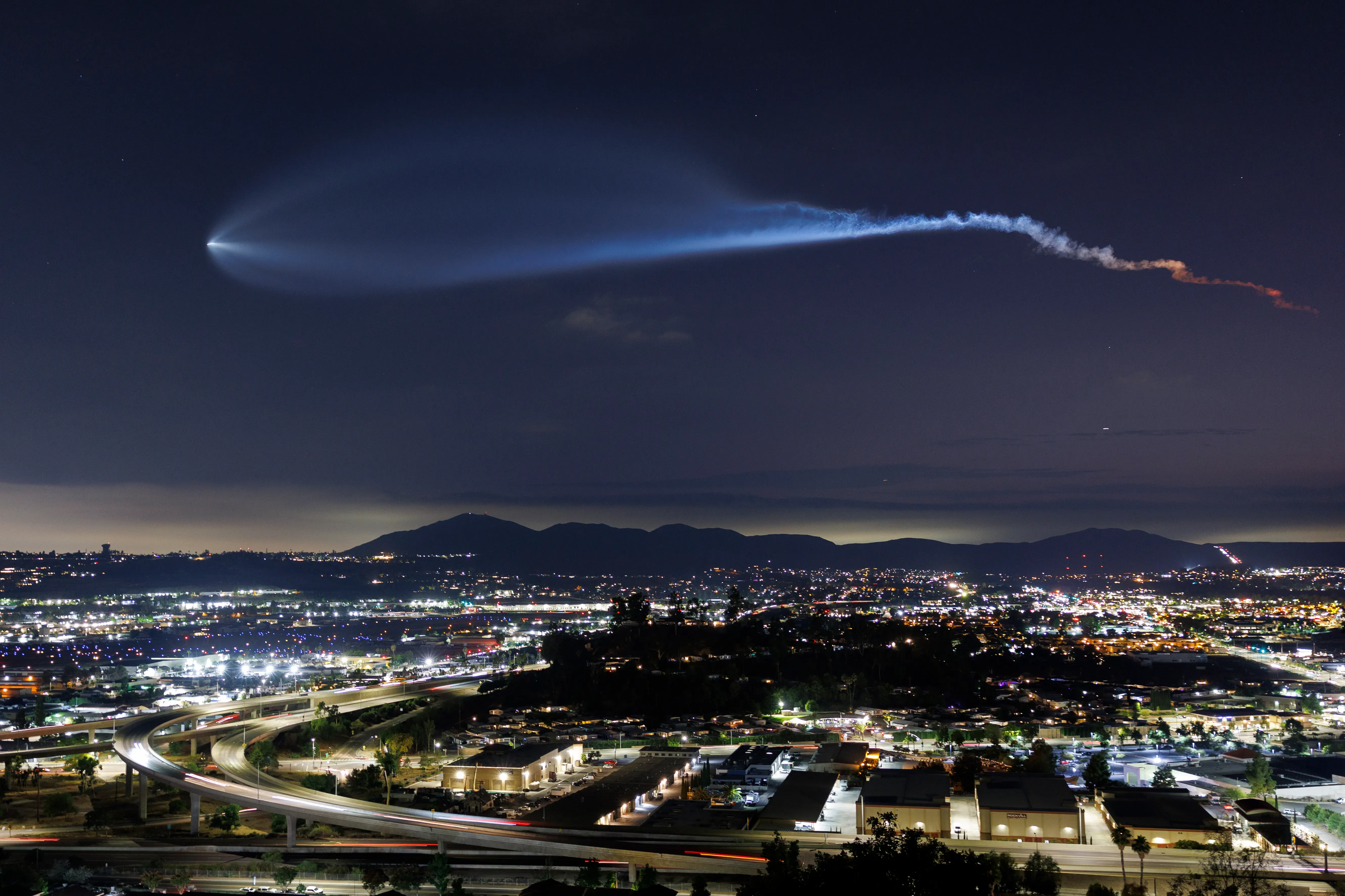A SpaceX Falcon 9 rocket carrying a payload of 24 Starlink internet satellites soars into space after launching from Vandenberg Space Force Base on July 18, 2025, seen from Santee, California.