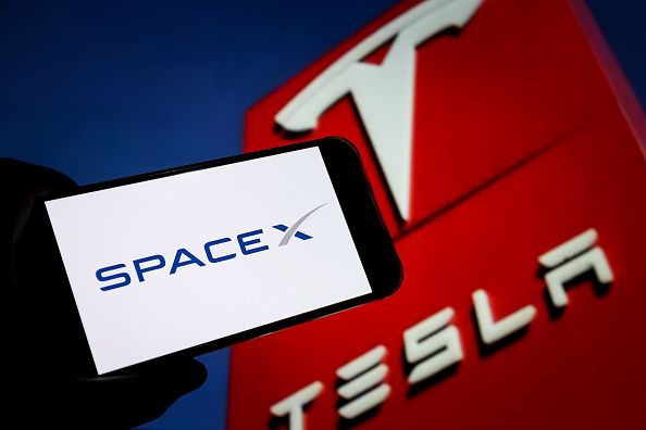 In this photo illustration, the logo of SpaceX is displayed on a smartphone screen with Tesla logo in the background on October 20, 2026 in Chongqing, China. (Photo by VCG/VCG via Getty Images)