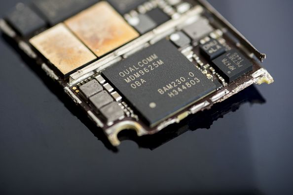 A Qualcomm Inc. baseband modem integrated circuit (IC) chip, center, of an Apple Inc. iPhone 6 smartphone is seen in an arranged photograph in Bangkok, Thailand. Photographer: Brent Lewin/Bloomberg via Getty Images