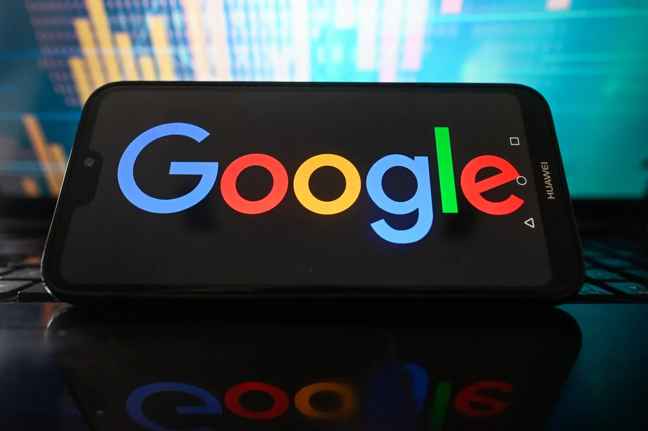 In this photo a Google logo is seen displayed on a smartphone with stock market percentages on the background. 