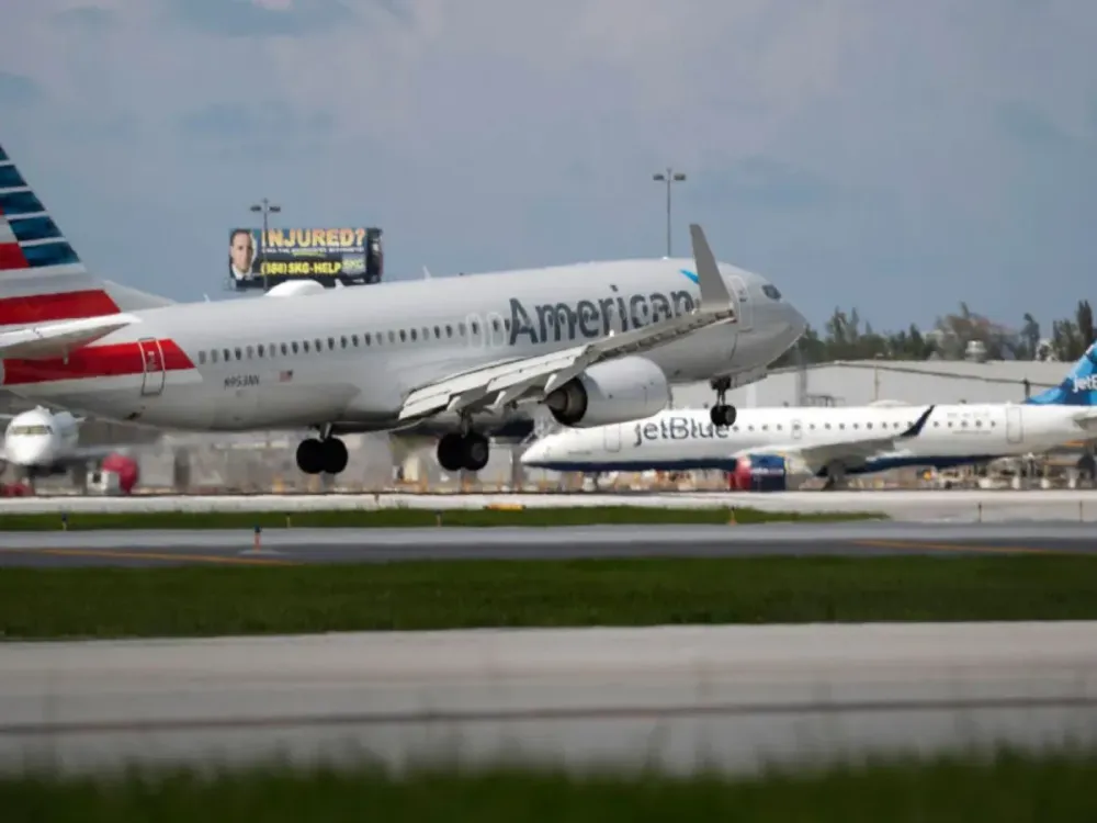 An American Airlines plane lands on a runway near a parked JetBlue plane at the Fort Lauderdale-Hollywood International Airport on July 16, 2020 in Fort Lauderdale, Florida.