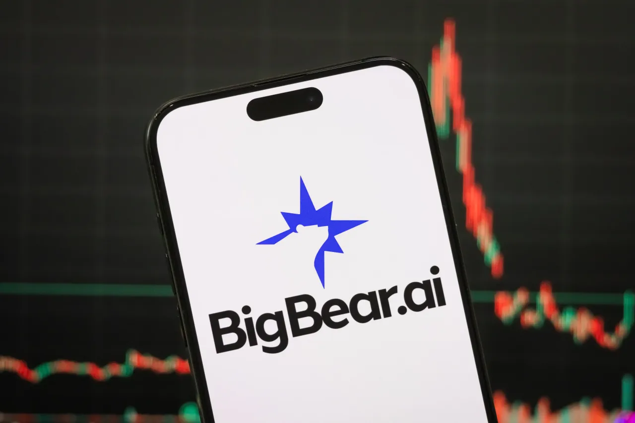 The logo of BigBear.ai Holdings, Inc. displayed on a smartphone screen, with the company's latest stock market chart visible in the background on April 26, 2025, in Chongqing, China. (Photo illustration credit: Cheng Xin/Getty Images)