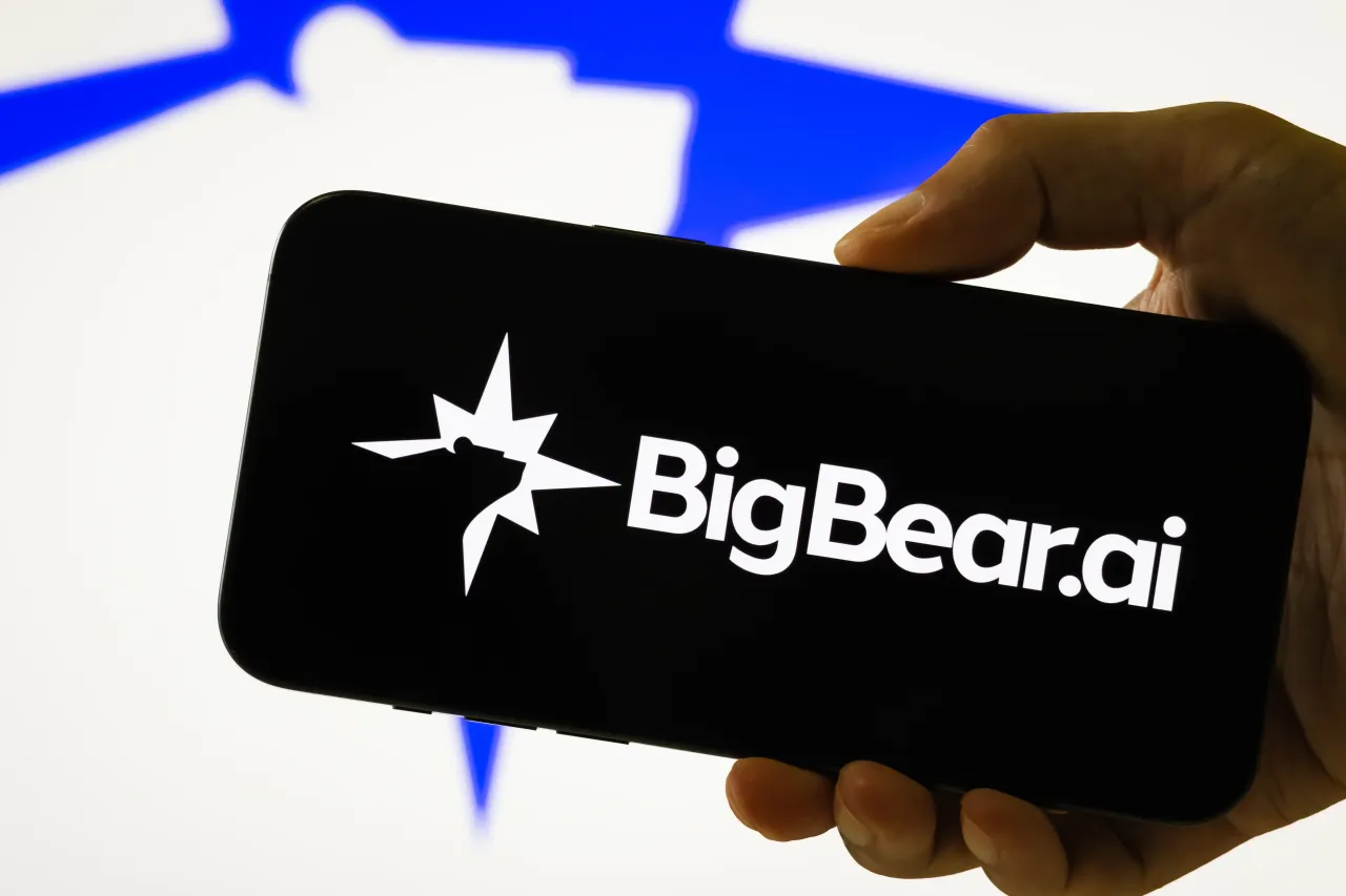 In this photo illustration, a person holds a smartphone displaying the logo of BigBear.ai Holdings, Inc. (NYSE: BBAI), on August 8, 2025, in Chongqing, China. (Photo illustration by Cheng Xin/Getty Images)