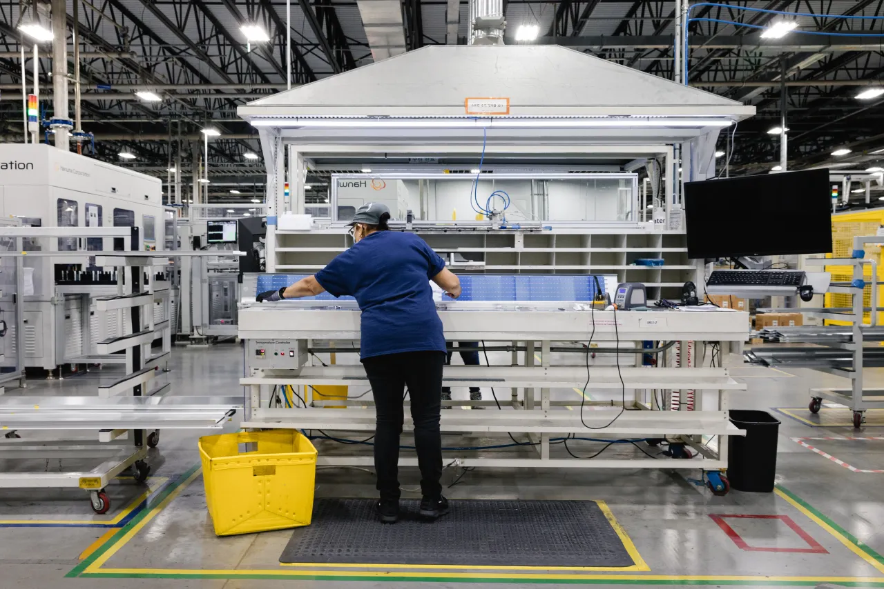 An employee performs quality control on a string of photovoltaic cells on the assembly floor at the Qcells solar panel. 