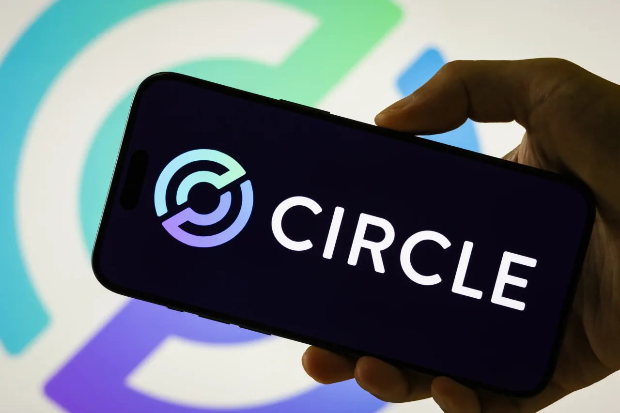 In this photo illustration, a person holds a smartphone displaying the logo of Circle (NYSE: CRCL), a global fintech company and issuer of the USDC stablecoin, on August 8, 2025, in Chongqing, China. 