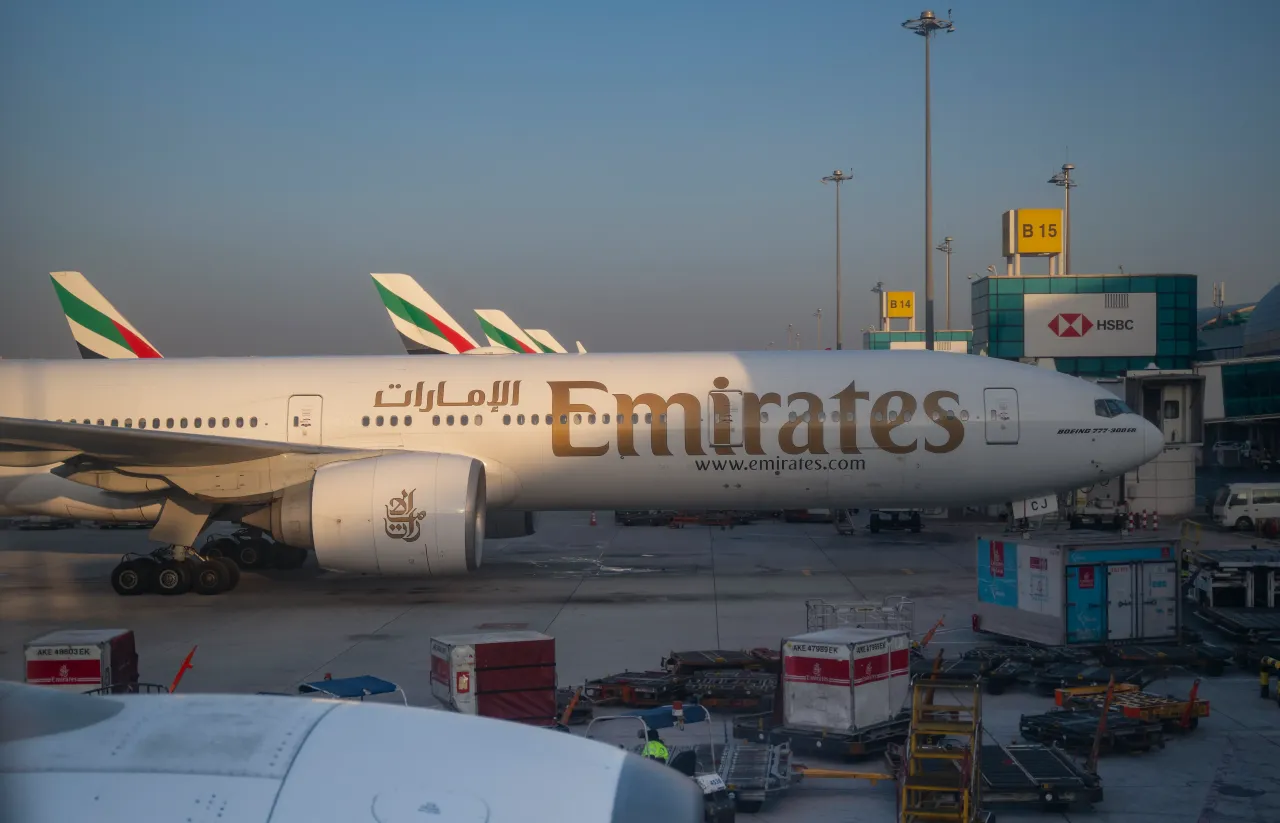 Ground personnel and cargo containers are seen under Emirates Boeing 777-300 ER aircraft sitting on the tarmac at Dubai International Airport on March 06, 2024, in Dubai, UAE.