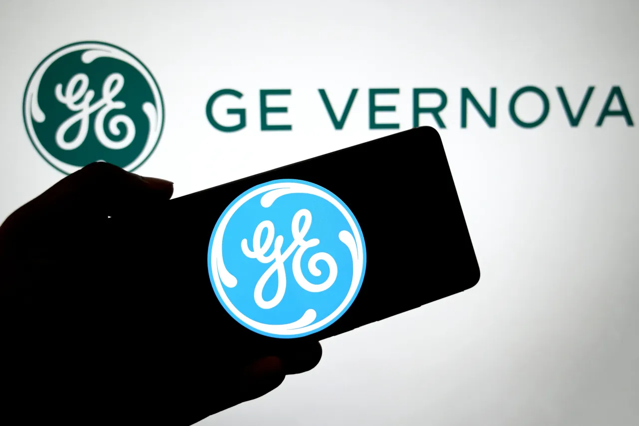 In this photo illustration, a GE logo is seen displayed on a smartphone with a GE Vernova logo in the background. 