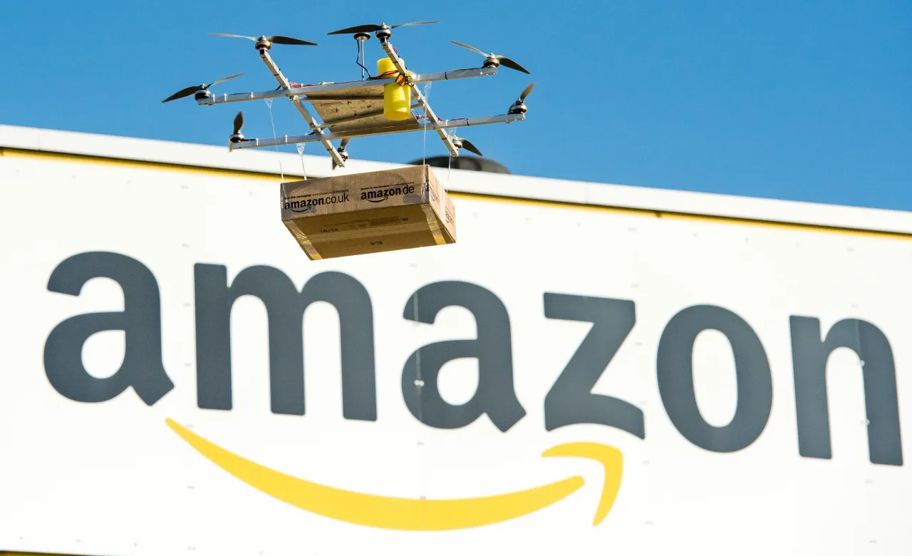 A drone with an Amazon package floats in front of the Amazon logistics center in Leipzig, Germany, 28 October 2014. (Photo by Peter Endig/picture alliance via Getty Images)