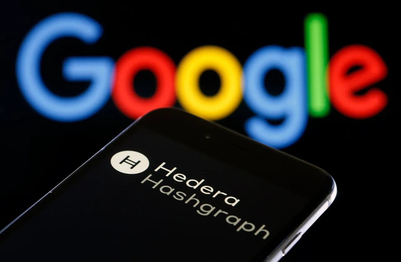 In this photo illustration, the Hedera Hashgraph logo is displayed on the screen of an iPhone in front of a computer screen displaying the Google logo on February 24, 2020 in Paris, France.