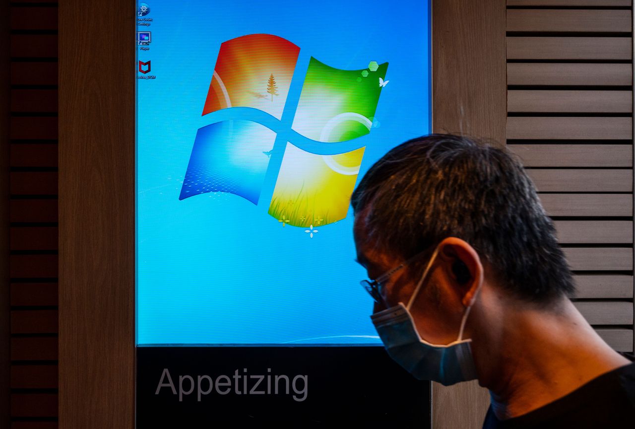 A man walks past a screen displaying Microsoft Windows logo in Hong Kong. (Photo by Budrul Chukrut/SOPA Images/LightRocket via Getty Images)
