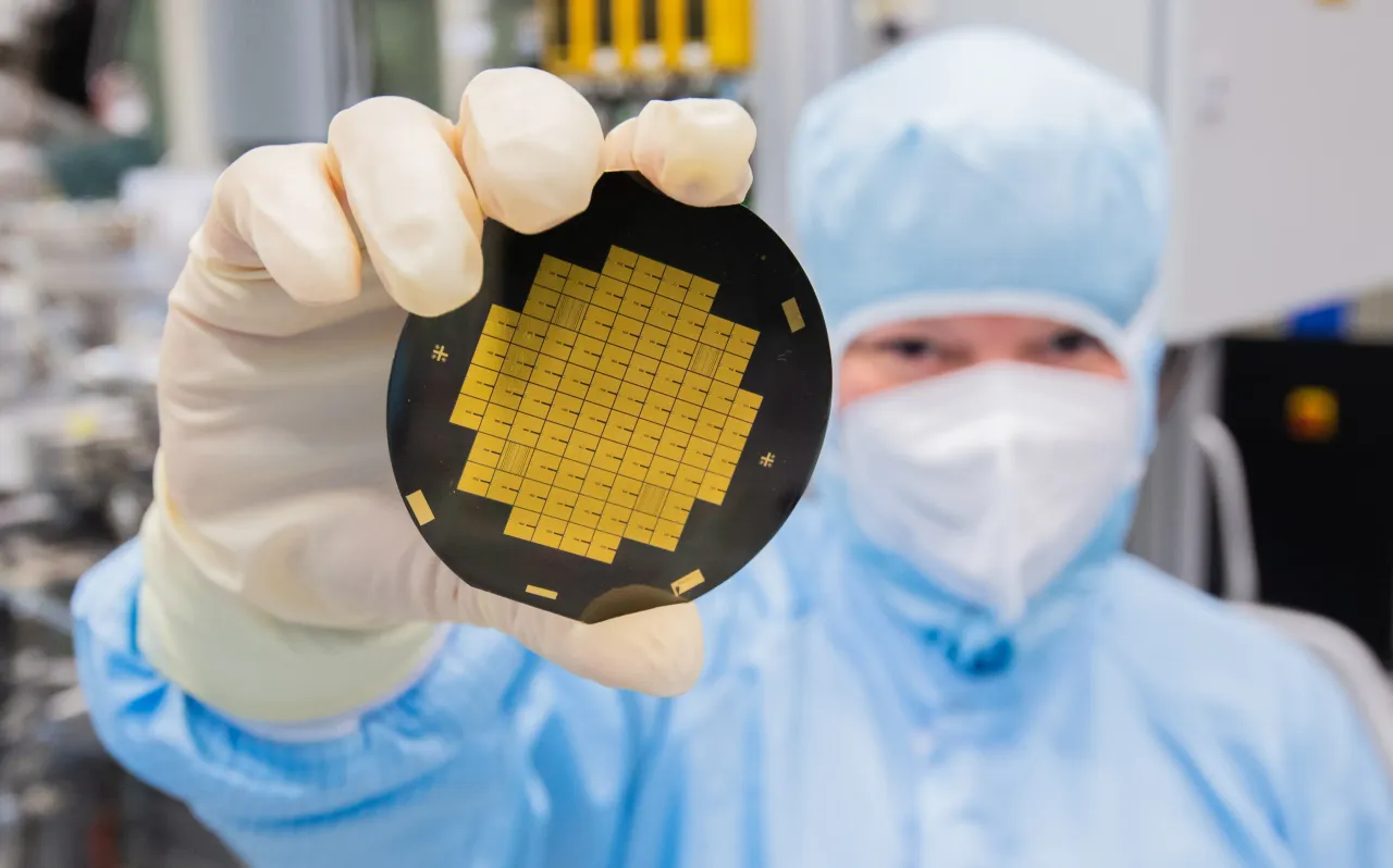 A research associate shows microchips for quantum processors in a clean room laboratory in Germany. (Photo by Julian Stratenschulte/picture alliance via Getty Images)