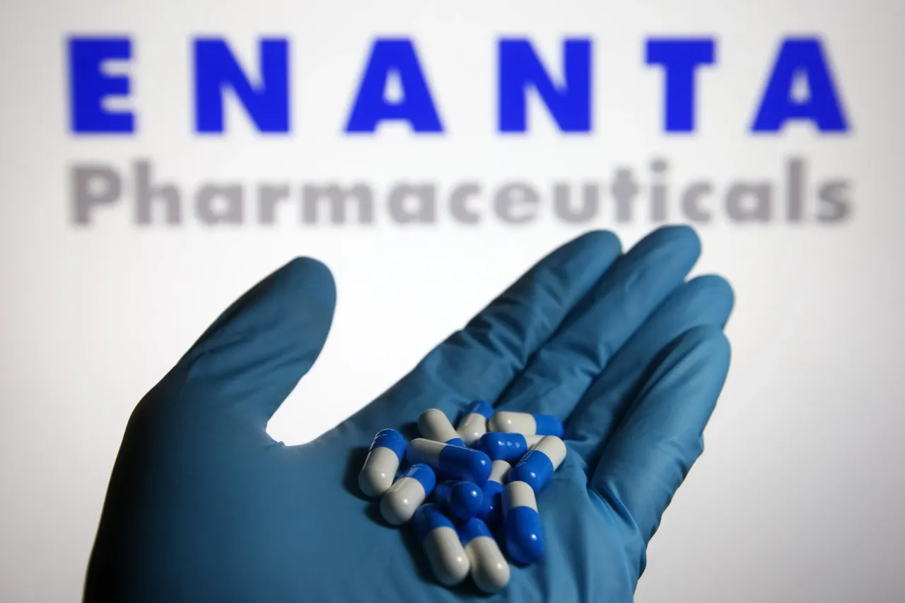 In this photo illustration, capsules are seen in a hand dressed in a medical glove with the Enanta Pharmaceuticals logo in the background. (Photo Illustration by Pavlo Gonchar/SOPA Images/LightRocket via Getty Images)