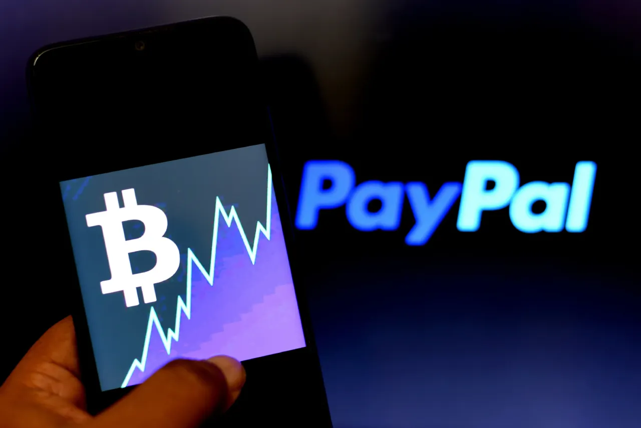  In this Photo illustration a Bitcoin logo seen displayed on a smartphone with a Paypal logo in the background.