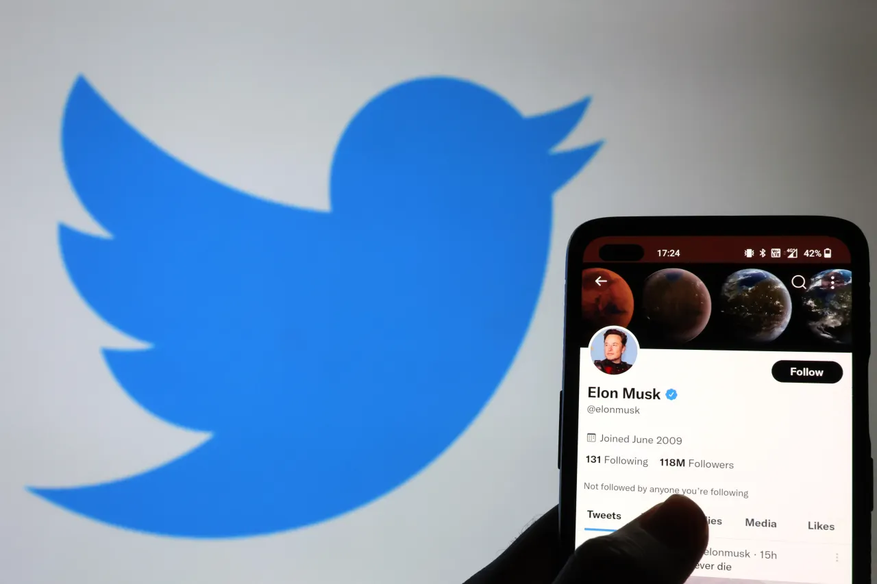 The Twitter account of Elon Musk is displayed on a smartphone with a Twitter logo in the background on November 21, 2022. (Photo by Nathan Stirk/Getty Images)