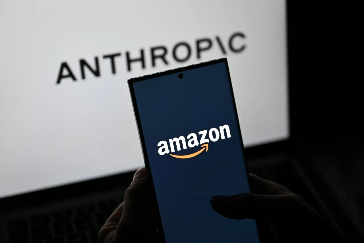 The logo of Anthropic is displayed on a mobile phone screen in front of the Amazon logo on a computer screen. (Photo by Harun Ozalp/Anadolu via Getty Images)