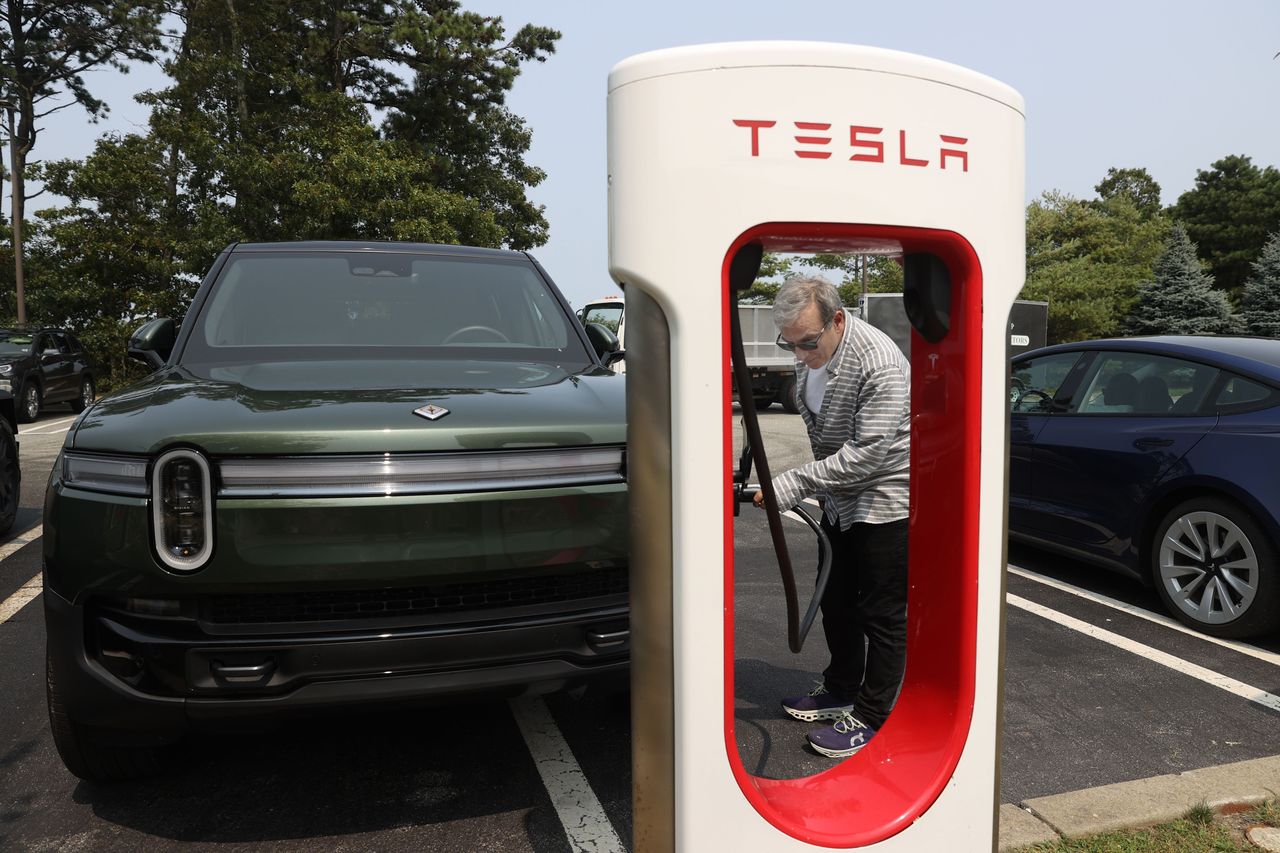Boston Globe reporter Aaron Pressman charges a Rivian SUV at a Tesla Supercharger. (Photo by Jonathan Wiggs/The Boston Globe via Getty Images)